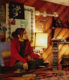 a woman sitting on top of a bed next to a lamp