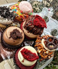 there are many different types of cupcakes on the glass plate and one is half eaten