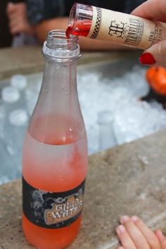 a bottle of beer being poured into an ice bucket with someone's hand reaching for it