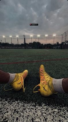 a pair of yellow shoes sitting on top of a soccer field