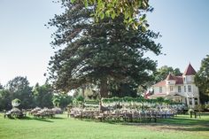 an outdoor wedding venue with tables and chairs set up in front of a large tree