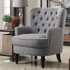 a gray chair sitting on top of a wooden floor next to a table and lamp