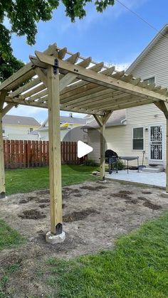 a wooden pergolan sitting in the middle of a yard