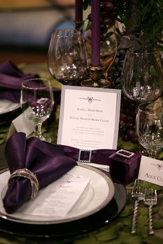 the table is set with purple napkins and place settings for an elegant dinner party