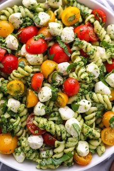 a pasta salad with tomatoes, mozzarella and pesto