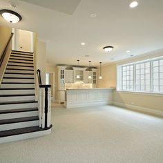 an empty living room with stairs leading up to the kitchen