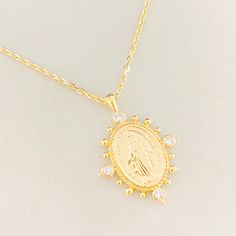 Stunner for those who seek a miraculous medal necklace in a trendy style. This simple yet gorgeous piece features a Virgin Mary charm that has written in Latin:"Queen conceived without original sin, Pray for us". The charm also features four bezel set crystals in a north- south- east- west- direction, with small bead details in between. Materials: white gold plating over 925 Sterling Silver or 14k Gold over 925 SS Chain and Charm measurements: Chain:16 " with 2 " extender; charm: 1"x.75" Gold Miraculous Medal Jewelry, Necklaces Virgin Mary, Mary Necklace Silver, Saint Necklace Silver, Silver Virgin Mary Pendant Jewelry, Miraculous Medal Necklace, Our Lady Of Fatima Necklace Vintage, North South, Pray For Us