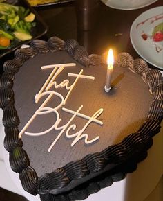 a chocolate heart shaped cake with the words that blob on it and a lit candle