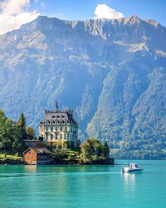 a house on an island in the middle of a lake with mountains in the background