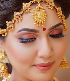 a woman wearing gold jewelry and red eyeshade, with her hair pulled back to the side