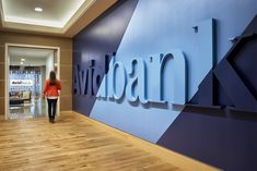 a woman is walking past a large sign on the wall