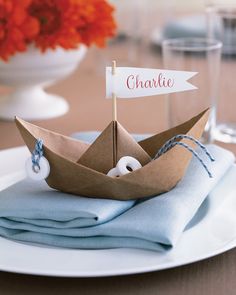 a paper boat is sitting on top of some folded napkins with a name tag