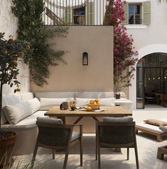 an outdoor dining area with white furniture and potted plants on the wall, next to stairs