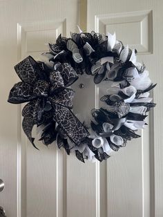 a black and white wreath hanging on the front door, with ribbons attached to it