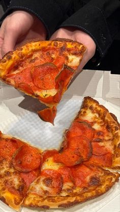 two slices of pepperoni pizza are being held by someone's hands over a white paper plate