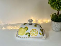 a decorative dish with lemons on it next to a potted plant