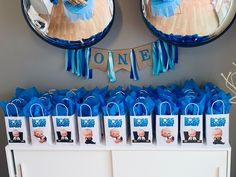 a table topped with blue bags filled with baby shower items and pictures hanging from the wall