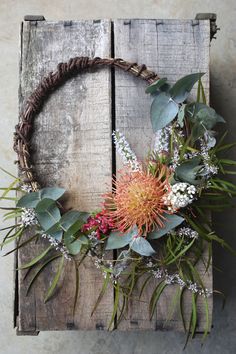 an arrangement of flowers and greenery on a wooden crate