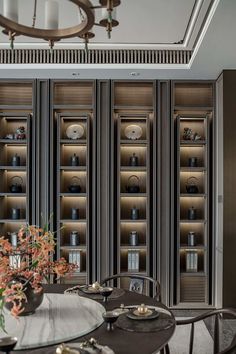 a dining room table with chairs and vases on it in front of bookshelves