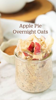 a glass jar filled with oatmeal and topped with sliced strawberries next to cinnamon sticks