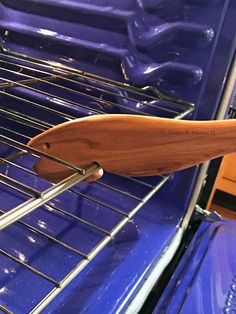 a wooden spatula is sticking out of an oven rack that has blue metal racks