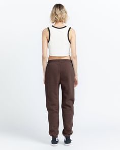 the back view of a woman wearing brown sweatpants and a white cropped tank top