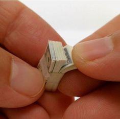 a person holding a tiny piece of money in their left hand, with the other end torn off