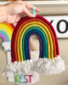 a hand holding a rainbow decoration with white feathers