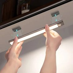 two hands are holding the light bar in front of a mirror