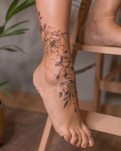 a woman's foot with a flower tattoo on her left leg and the bottom part of her body visible