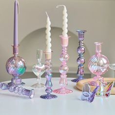 a table topped with lots of different colored glass vases and candlesticks next to each other