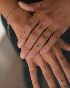 two people holding each other's hands with stars tattooed on their fingers, both wearing gold rings