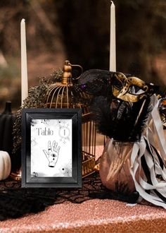 a table topped with candles and decorations next to a birdcage filled with feathers