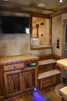 a kitchen with wooden cabinets and a flat screen tv mounted to the side of the wall