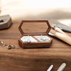 an open wooden box with two wedding rings inside on a table next to other items