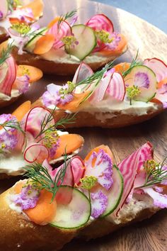 several pieces of bread with various vegetables on them sitting on a wooden platter, ready to be eaten