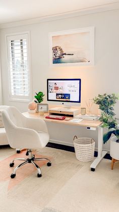 a desk with a computer, chair and potted plant in front of the monitor