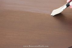 a person is using a brush to paint a wooden table with woodgrains on it