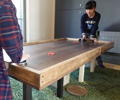 two people playing a game on a table in a room with carpeted flooring