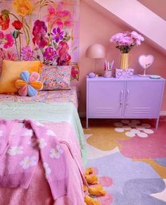 a bedroom decorated in pastel colors with flowers on the wall