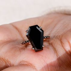 a woman's hand holding a black stone ring on top of her finger,