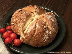 a black plate topped with a loaf of bread and cherry tomatoes