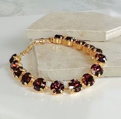 This gorgeous Burgundy Crystal and Gold Bracelet is great alone or stacked to make a fabulous statement! It features stunning Austrian crystals, carefully hand-set in a delicate gold chain. The perfect accessory for any occasion, this stacking bracelet will add a touch of elegance to your outfit. Details * 14K Gold-plated Cup Chain Bracelet * Premium Crystals- 8mm (5/16") Burgundy Chaton Crystal * Bracelet Length- Adjustable from 7 to 8 1/2 inches * Tarnish Resistant * Nickel and Lead-free The b Adjustable Gold Bracelet, Cup Chain Bracelet, Gold Armband, Burgundy And Gold, Austrian Crystal, Bracelet Stack, Jewelry Bags, Chain Link Bracelet, Crystal Bracelets