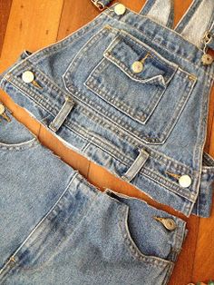 an old pair of denim overalls with holes in the front and back, sitting on a wooden floor