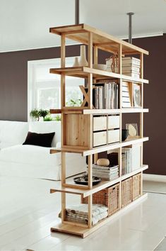 a living room with a white couch and book shelf in the middle, filled with books