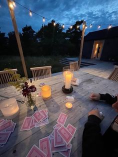 a person sitting at a table with playing cards on it and candles in front of them