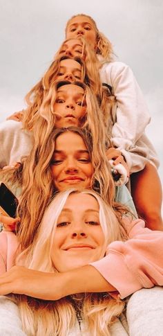 a group of women sitting on top of each other with their arms around one another