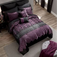 a bed with purple and black comforters in a room