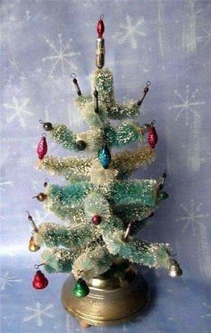 a small white christmas tree sitting on top of a metal stand with ornaments around it