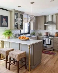 a kitchen with two stools in front of the counter and an island that has fruit on it